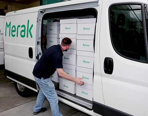 Koerier van Merak die bestelwagen ingeladen heeft met archiefdozen