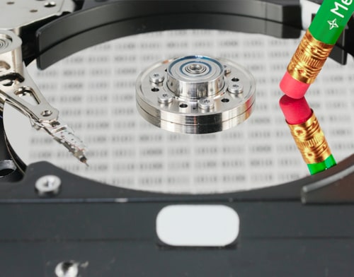 Close-up of a hard disk with a pencil gumming on it