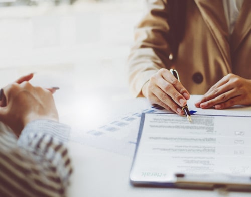 Two people at a desk fill out an agreement