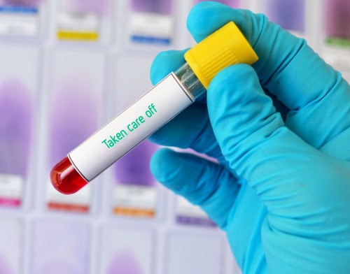 One hand holds a blood sample with inscription 'taken care off'