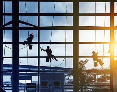 Three window washers tied to a tall building with large windows